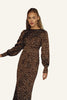 A woman wearing a long-sleeved brown maxi dress with a white polka dot pattern.