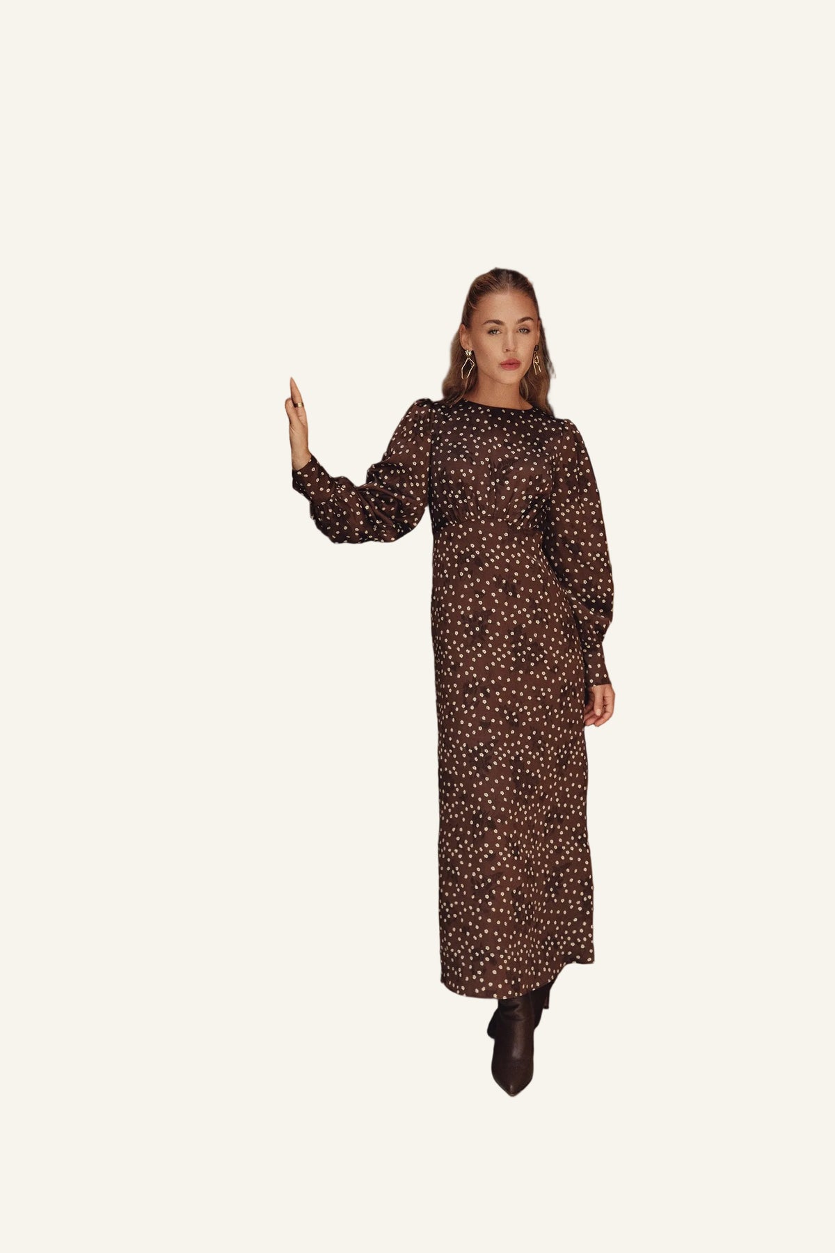 A woman wearing a brown long-sleeve maxi dress with a small white floral pattern and brown ankle boots.