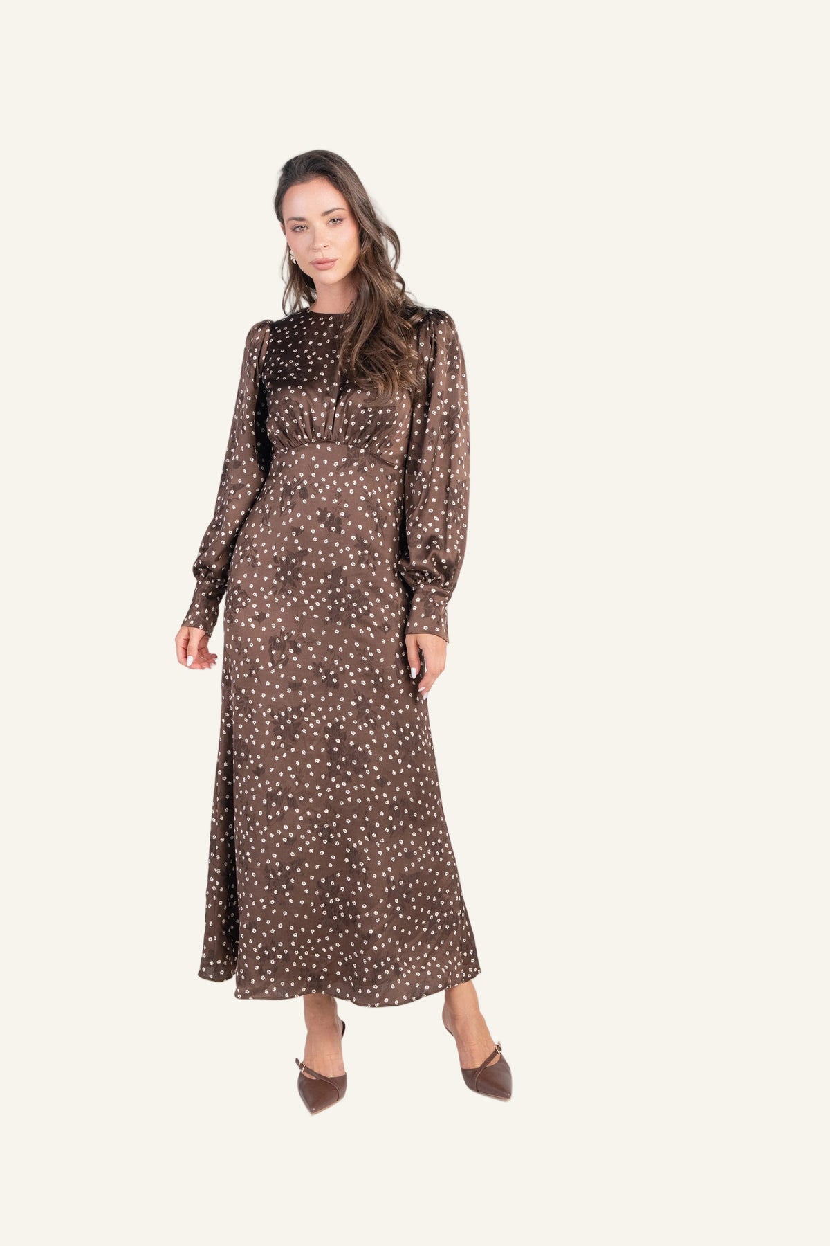 A woman modeling a long-sleeved brown midi dress with a white polka dot pattern.