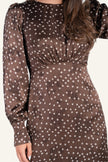 A woman wearing a brown long-sleeve dress with a white floral print. 