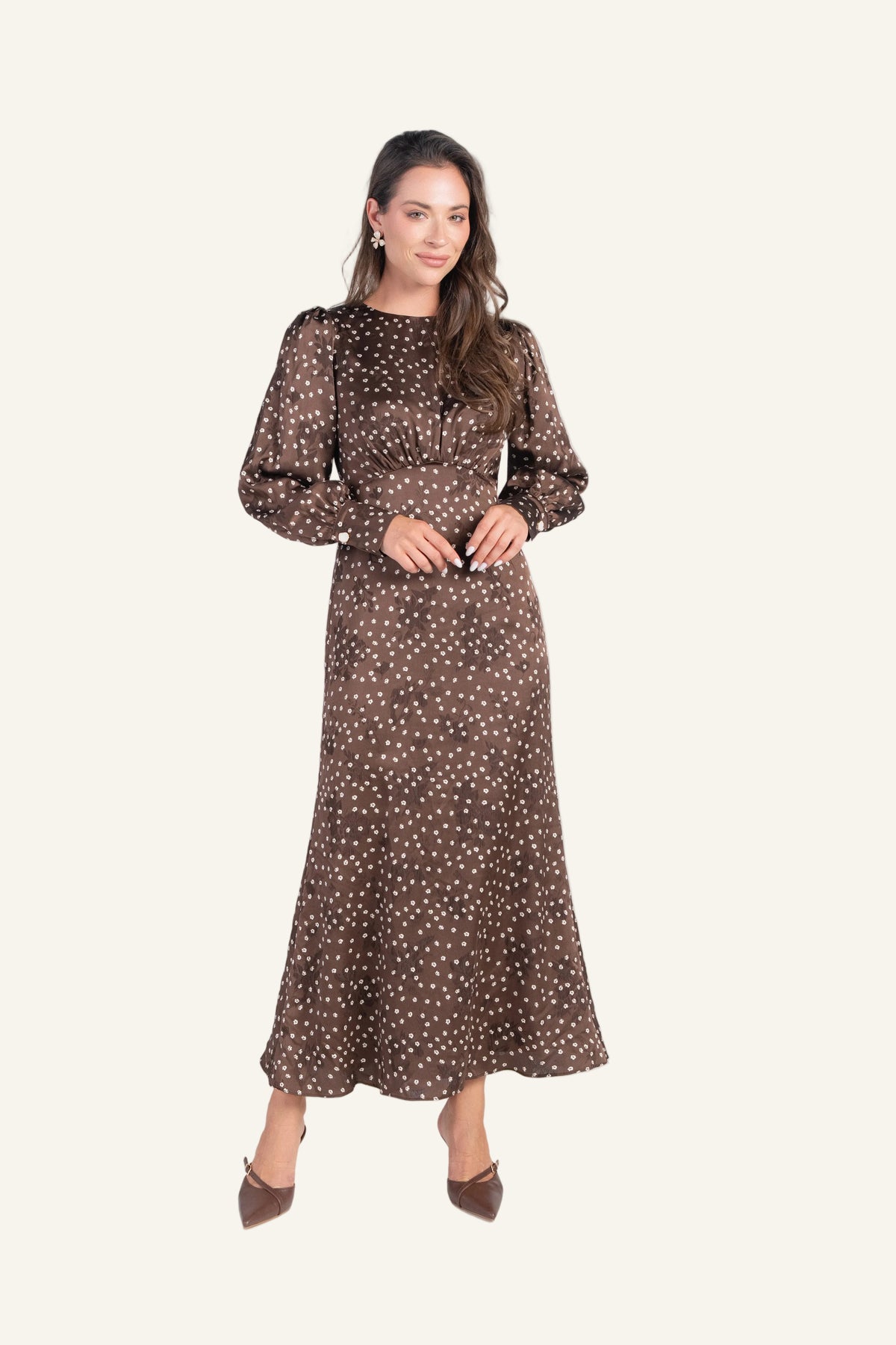 A woman modeling a long-sleeved midi dress with a brown and white polka dot pattern.