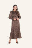 A woman modeling a long-sleeved midi dress with a brown and white polka dot pattern.
