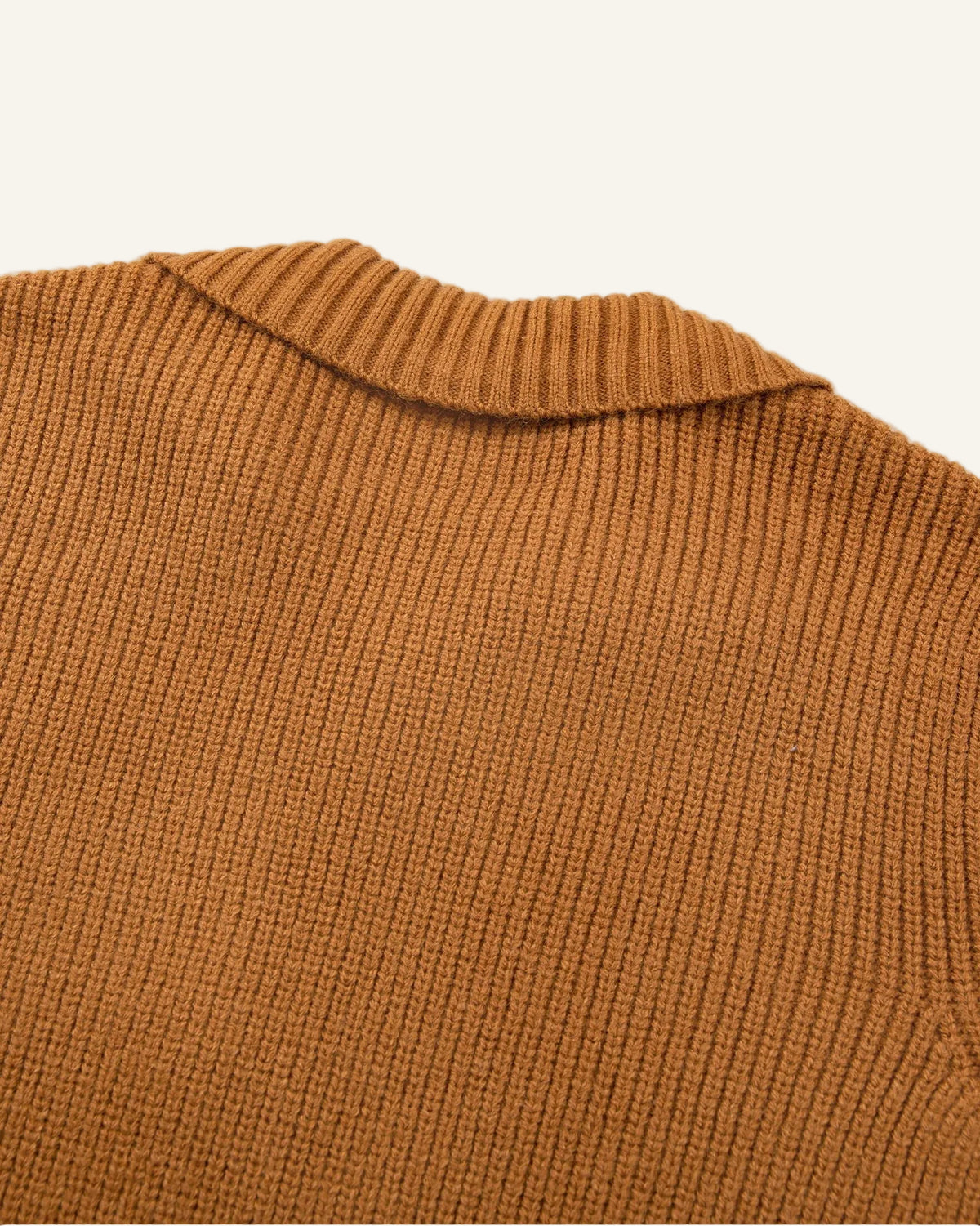 Close-up of a ribbed knit sweater in a warm camel brown color, showing the texture and collar detail.