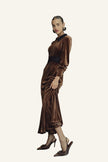 A woman models a brown velvet midi dress with a black collar and waistband, paired with brown pointed-toe heels.
