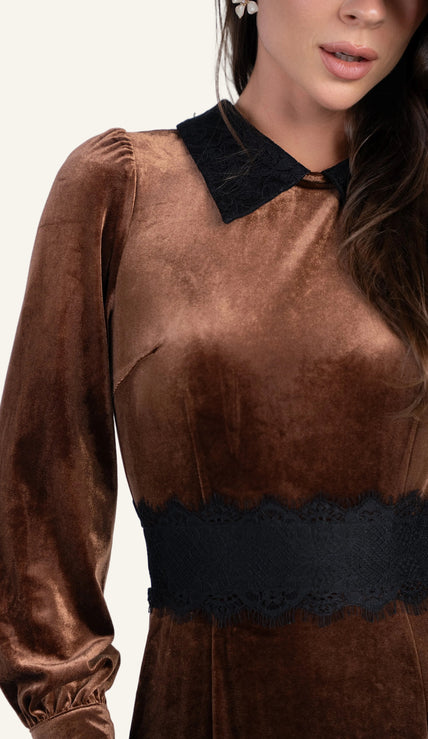 A close-up of a woman wearing a brown velvet long-sleeve dress with a black lace collar and a matching black lace waistband.