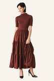 A woman modeling a short-sleeve mock-neck midi dress in a deep burgundy color, paired with black high heels.