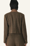 Back view of a model wearing a brown tweed cropped jacket and matching trousers.
