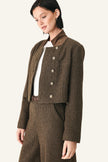 A model wearing a brown and black micro-check cropped jacket with a high collar and silver buttons, paired with matching brown trousers and a white top.