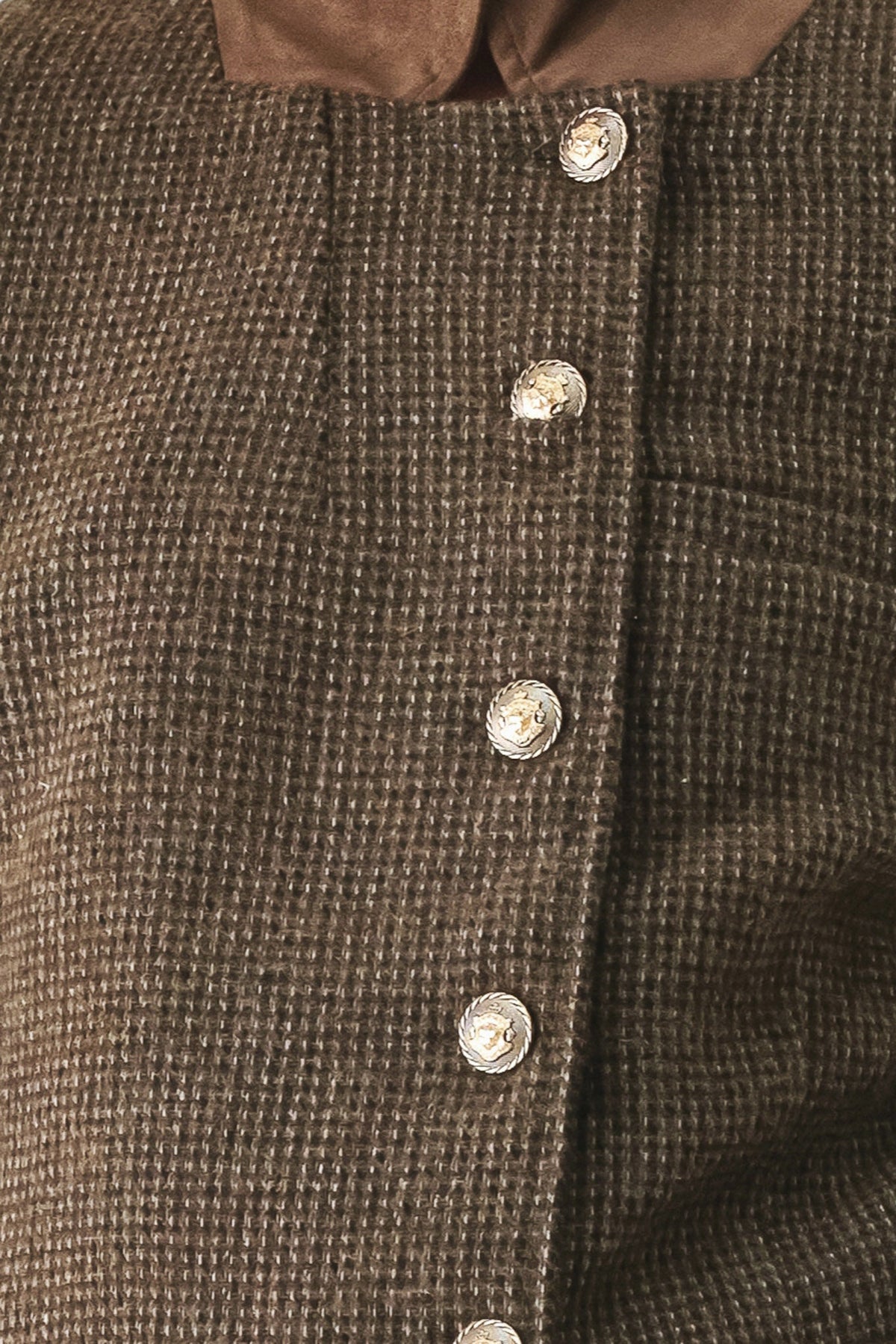 Close-up of a brown textured tweed button-up garment with a contrasting brown collar and shiny silver buttons.