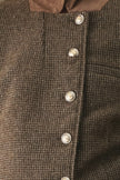 Close-up of a brown textured tweed button-up garment with a contrasting brown collar and shiny silver buttons.