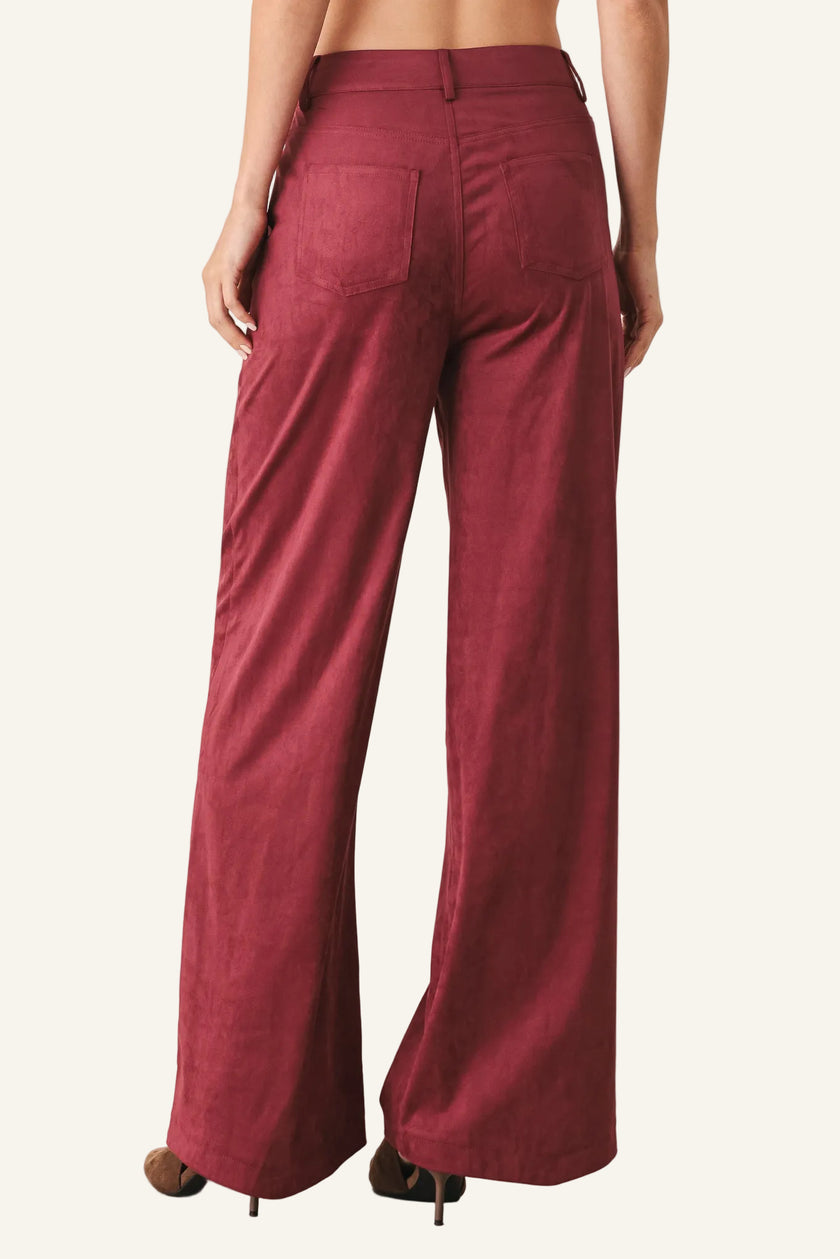 A person shown from the back wearing high-waisted, wide-leg trousers in a deep burgundy red. The pants feature a straight-to-slightly-flared leg, a waistband with belt loops, and two back patch pockets.