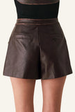 Brown faux-leather shorts with a structured silhouette, back pockets, and a thin brown leather waistband, shown on a model from the back.