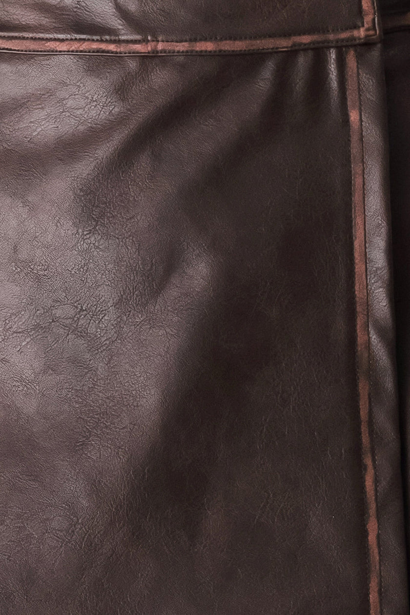 Close-up of dark brown textured leather with visible grain and a thin contrasting stitched seam.