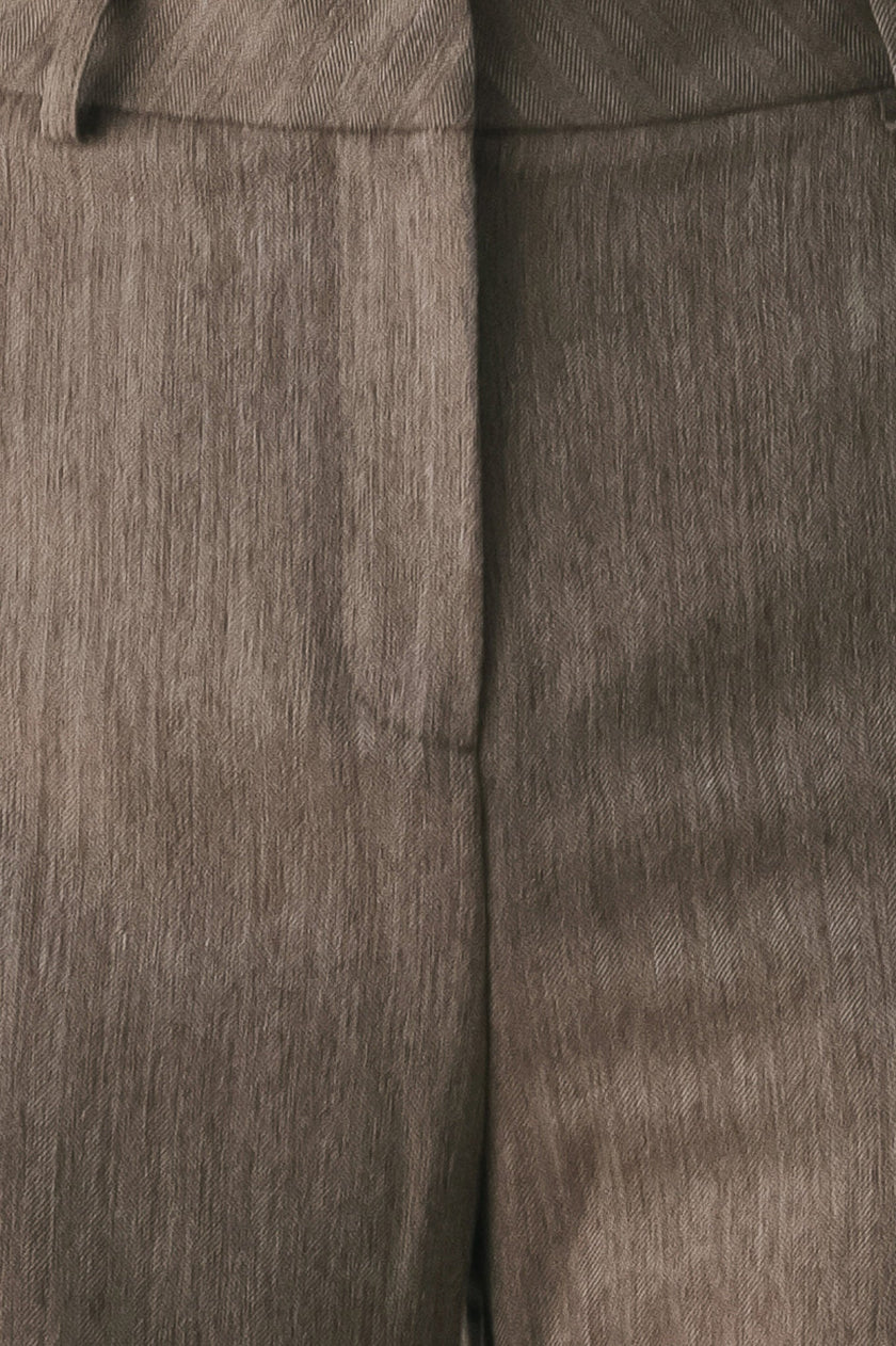 Close-up of a textured taupe-brown fabric garment, showing the weave and a central seam.