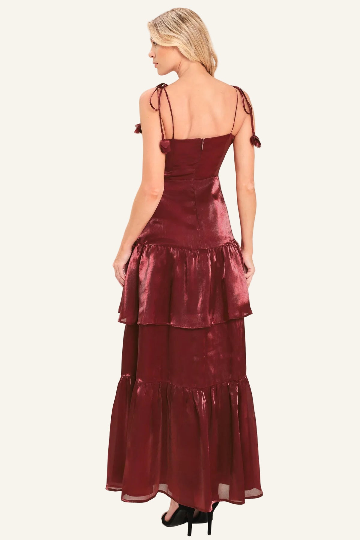 A woman modeling a long, sleeveless burgundy dress. The dress has tie straps, a fitted corset-style bodice, and a tiered ruffled skirt.