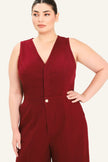 A woman modeling a sleeveless burgundy jumpsuit with a V-neckline and front button detail, photographed against a plain light beige studio background.