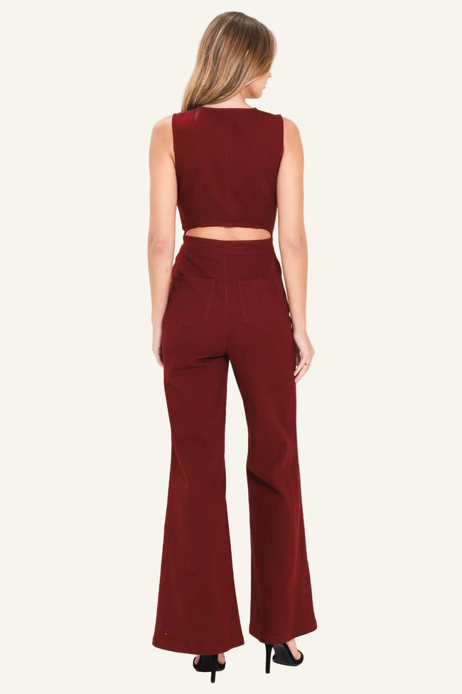 A woman viewed from the back wearing a sleeveless maroon crop top and matching maroon wide-leg pants, paired with black heels, against a plain light background.
