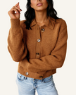 A woman wearing a brown ribbed knit button-front cardigan with a collar and light-wash blue jeans.